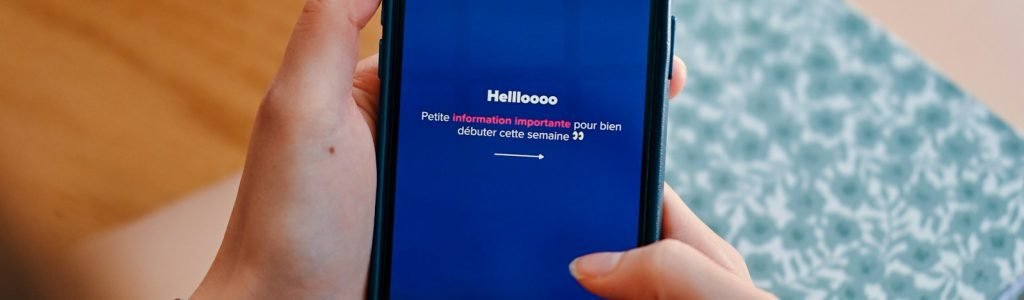 Mains tenant un smartphone qui affiche un fil de réseau social